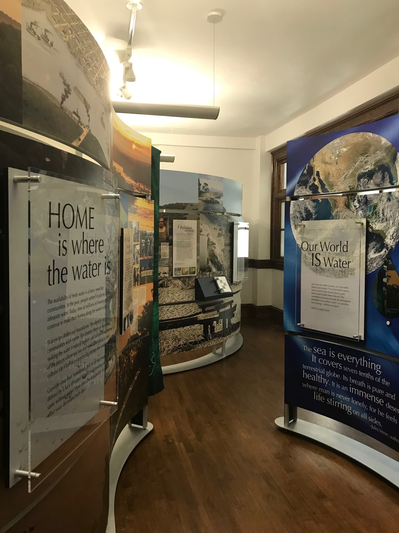 Image of the water ways exhibit installed. Three curved panels can be seen, one on the right, left, and in the background. 